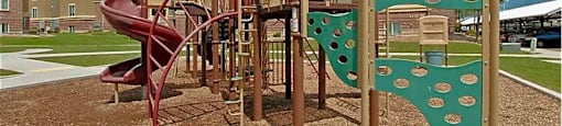A playground with a red slide and a green climbing structure.