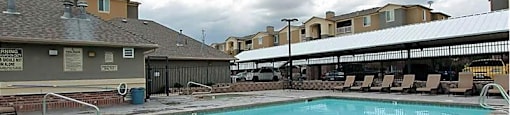 A large swimming pool with a concrete floor and a metal fence around it.