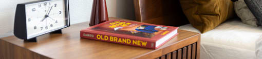 a clock and a book on a night stand next to a bed at Analog PDX Apartments, Oregon 97227