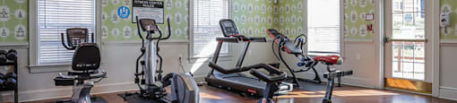 A gym with exercise equipment and a patterned wallpaper.