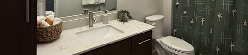 A bathroom with a toilet, sink, and mirror.