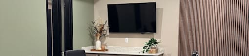 A room with a desk, chairs, and a wall with a patterned wallpaper.