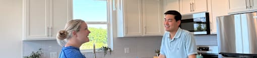 A man and a woman are standing in a room with a white ceiling and a window.