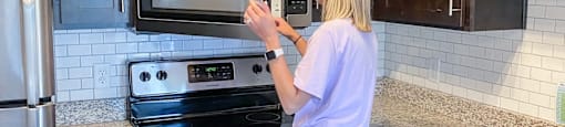 A woman is standing in a kitchen with a microwave.