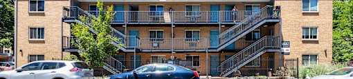 A multi-story apartment building with cars parked in front at 1303 Columbine in Denver, CO