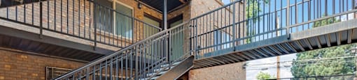 A black metal staircase with a glass balustrade leads to a balcony at 23–33 Pearl St in Denver, CO
