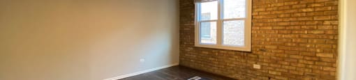 Bedroom with wood flooring and exposed brick wall