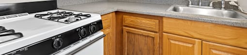 A kitchen with a white stove and wooden cabinets 1170 N Logan St in Denver, CO