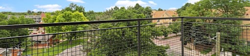 A balcony with a black railing overlooks a green lawn and a brick building  at 4805 E Kentucky in Denver, CO