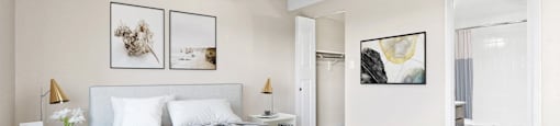 A bedroom with a large bed and two framed pictures on the wall.