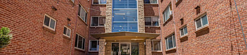 A brick building with a glass entrance and a stone pathway leading to it.
