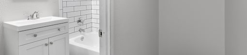A white bathroom with a white cabinet and a white tub at 1355 Pearl in Denver, CO