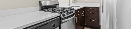 A white dishwasher is in a kitchen with dark brown cabinets at 1444 Saint Paul St in Denver, CO
