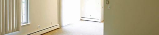 an empty living room with white walls and a window