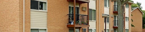 a brick apartment building with balconies and a tree