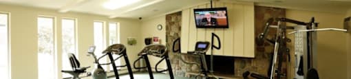 a gym with exercise equipment and a tv on the wall