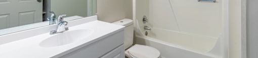 A white bathroom with a toilet, sink, and bathtub.