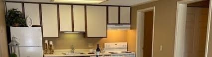A kitchen with a white counter and wooden flooring.