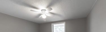 A room with a ceiling fan and a window.