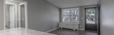 A spacious room with a marble floor and a window with blinds.