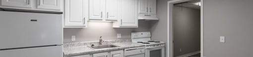 A kitchen with white cabinets and granite countertops.