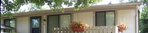 A small house with a white picket fence and hanging flower pots.