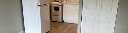 A kitchen with a white fridge and a white door.