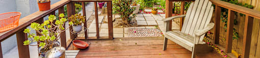 A wooden deck with a bench and a table with flowers on it.