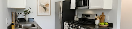 A kitchen with white cabinets and black countertops.