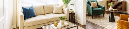 A living room with a white sofa, a green armchair, a coffee table, and a lamp.