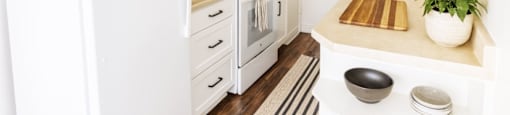 A white refrigerator stands in a kitchen with a sink and a mirror.