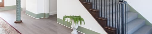 A staircase with a green pole and a plant on the landing.