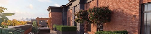 A modern outdoor seating area with a brick wall and greenery.