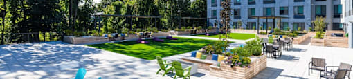 an outdoor patio with blue chairs and a lawn in front of a building