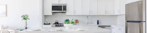 a kitchen with white cabinets and a large island with three stools