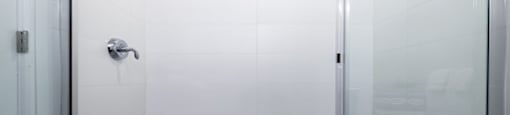 a glass shower stall in a white tiled bathroom