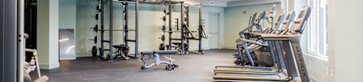 a gym with treadmills and other exercise equipment in a room with windows
