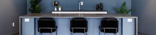 a kitchen with blue walls and a counter with three stools