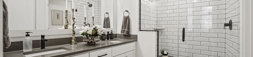 A modern bathroom with a white tile shower and a vanity with a mirror above it.