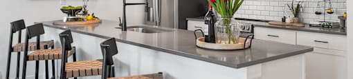 A kitchen with a grey countertop and white cabinets.