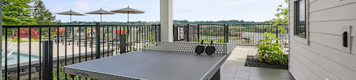 A patio with a table and chairs overlooking a pool.