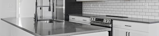 A kitchen with white cabinets and black appliances.