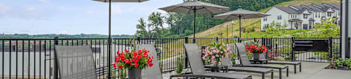 A patio with chairs and umbrellas overlooking a green landscape.