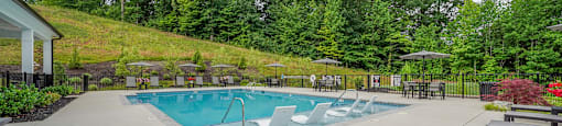 A pool surrounded by trees and a hill.