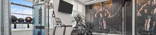 A gym with a variety of equipment including a treadmill, weights, and a bench.