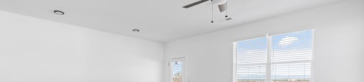 A room with a ceiling fan and a window with blinds.