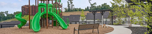 A playground with a green slide and a wooden structure.