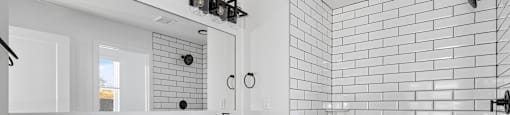 A white bathroom with a black and white tiled shower.