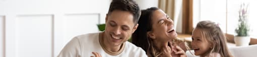A family of four is sitting on a couch, sharing a joyful moment together.
