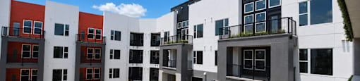A modern apartment complex with a pool in the courtyard.
